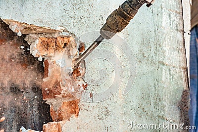 Disassembly of walls and openings with an electric jackhammer, close-up, dust hoarse from under the chisel Stock Photo
