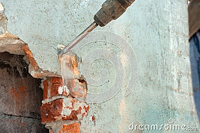 Disassembly of walls and openings with an electric jackhammer, close-up, dust hoarse from under the chisel Stock Photo