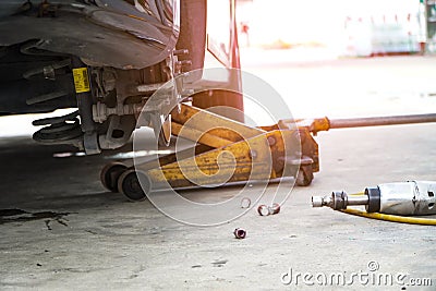 Disc brake of the vehicle for repair,Seal a leaking car tire.Car brake repairing in garage.Dirty Yellow Hydraulic Jack Forklift Stock Photo
