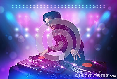 Disc jockey mixing music on turntables on stage with lights and Stock Photo