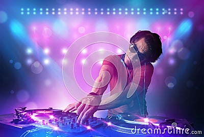 Disc jockey mixing music on turntables on stage with lights and Stock Photo