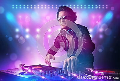 Disc jockey mixing music on turntables on stage with lights and Stock Photo