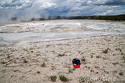 Discarded baseball hat littered and thrown in the fountain paint pots geysers and geothermal features of the lower geyser basin in Stock Photo
