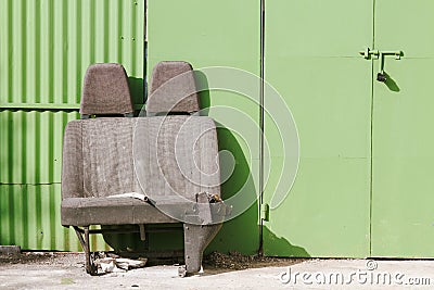 Discarded car seats in front of a green garage door Stock Photo