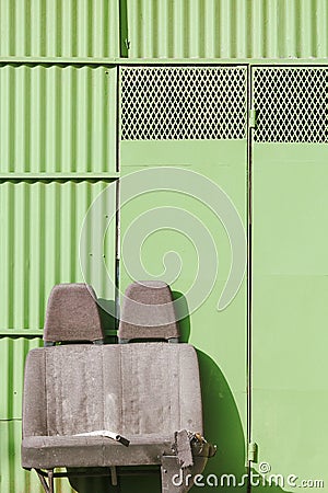 Discarded car seats in front of a green garage door Stock Photo