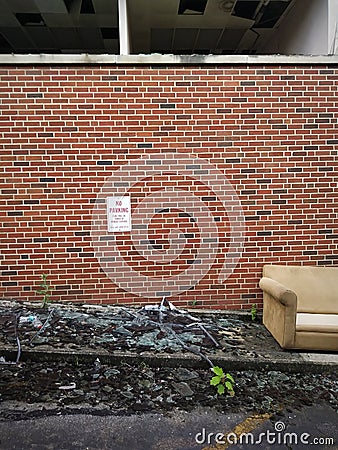 Abandoned Couch and Red Brick Wall Exterior of Abandoned Building Background. Stock Photo
