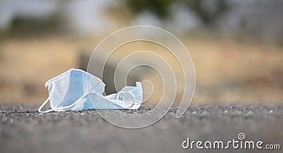 Discarded medical face mask stuck into road - concept of unhygienic dispose of masks helps to spread covid-19 or coronavirus Stock Photo