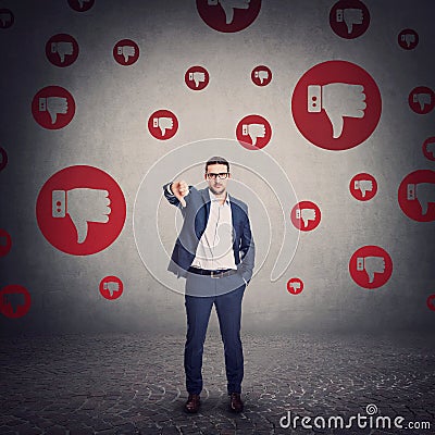 Discontent businessman looks displeased showing thumb down gesture. Negative feedback, upset business person and disapproval signs Stock Photo