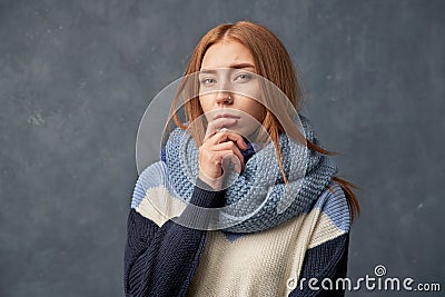 Red haired thoughtful girl holds fingers mouth Stock Photo