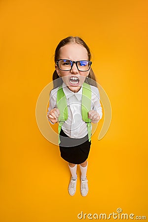 Discontented Schoolgirl In Eyeglasses Frowning Standing On Yellow Studio Background Stock Photo