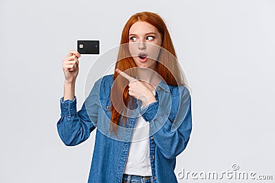 Discounts, shopping and banking concept. Waist-up impressed, thrilled cute redhead girl in denim shirt holding credit Stock Photo