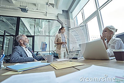 Discussing business strategy. Positive young race woman standing near flipchart and giving presentation, having a Stock Photo