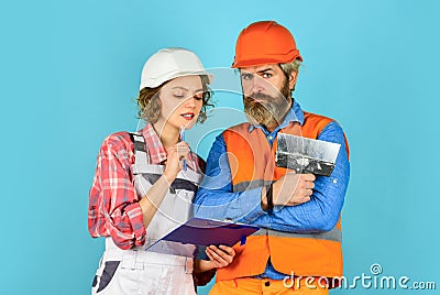 Discussing renovation with contractor. Plastering works. Couple look documents. Woman and man safety hard hat. Couple Stock Photo