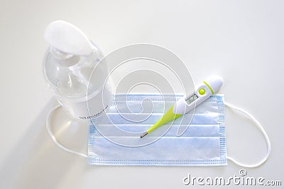 Medical face mask, alcohol gel dispenser and thermometer. Stock Photo