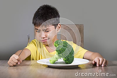 Disgusted child refusing to eat healthy green broccoli feeling upset in kid nutrition education on healthy fresh food and young Stock Photo