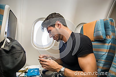 Disgusted man tasting insipid food in plane Stock Photo