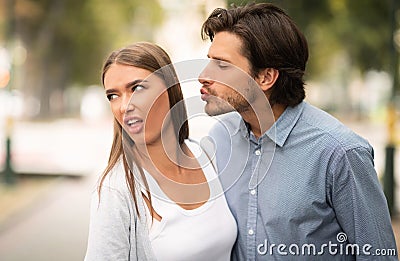 Disgusted Woman Rejecting To Kiss Man Walking Outdoors In Park Stock Photo