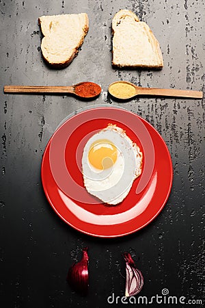 Dish with fried egg near spoons with spices, bread slices Stock Photo