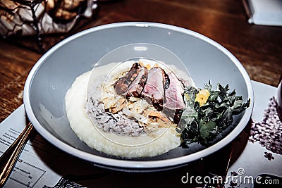 a dish of mashed pieces of meat of greens and stewed cabbage on a beautiful plate that stands on a table Stock Photo