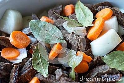 Dish with meat, carrots, onions and laurel on a black pan Stock Photo