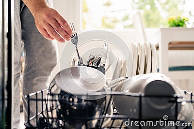 Dish washing powder. Dishwasher detergent and soap. Man loading washer machine. Dirty plates. Household technology. Stock Photo