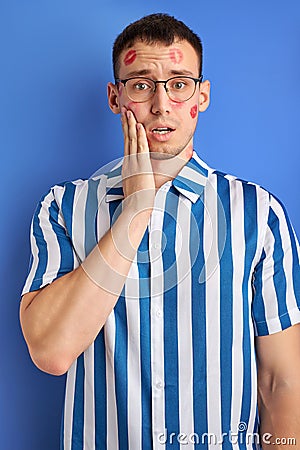 disheveled young man with traces of kiss on cheek look at camera in shock Stock Photo