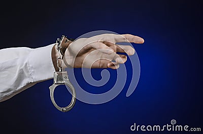 Dishonest and a prison doctor topic: the hand of man in a white shirt with handcuffs on a dark blue background in studio, put hand Stock Photo