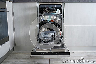 Dishwasher machine, open and loaded with dishes in the kitchen, after washing. Front view Stock Photo