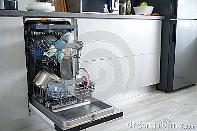 Dishwasher machine, open and loaded with dishes in the kitchen, after washing Stock Photo