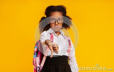 Displeased Black Schoolgirl Gesturing Thumbs-Down Disapproving Something Over Yellow Background Stock Photo