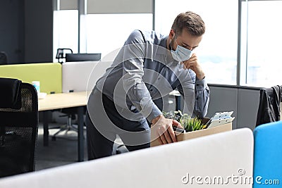 Dismissal employee in an epidemic coronavirus. Sad dismissed worker are taking his office supplies with him from office Stock Photo