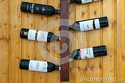 Display of Alentejo wine bottles on wall-mounted rack in a rustic restaurant. Editorial Stock Photo