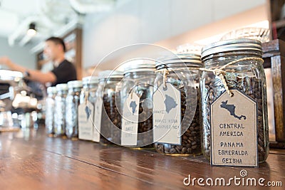 Varieties of specialty coffee beans from many countries in glass mason jars display for clients on the wooden counter at the coffe Stock Photo