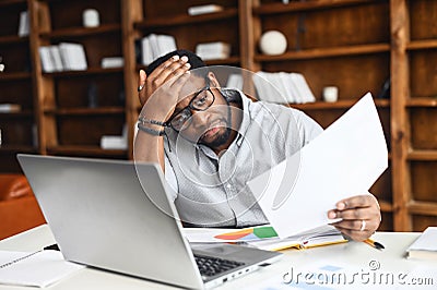 stressed black male employee reading a document bank statement Stock Photo