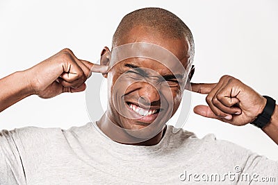 Displeased african man closes ears from a noise. Stock Photo