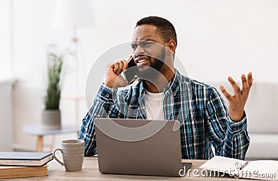 Displeased Black Guy Talking Having Quarrel By Phone At Workplace Stock Photo