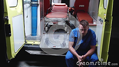 Sad corpsman sit in ambulance car at night. Stock Photo