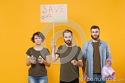 Displeased protesting young people hold protest broadsheet placard plastic bottles, trash bag isolated on yellow Stock Photo