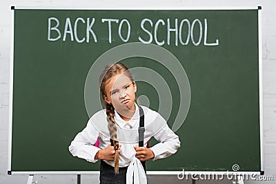 Displeased schoolgirl with heavy backpack near Stock Photo