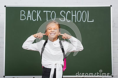 Displeased schoolgirl plugging ears with fingers Stock Photo