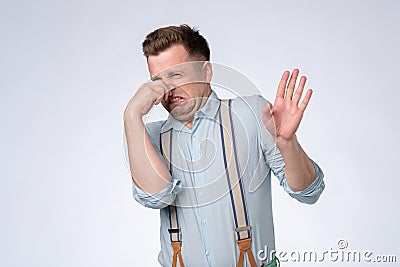 Displeased young man plugs nose as smells something stink and unpleasant. Stock Photo