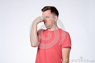 Displeased young man plugs nose as smells something stink and unpleasant. Stock Photo