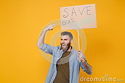 Displeased young protesting man point index finger on protest sign broadsheet placard on stick isolated on yellow Stock Photo