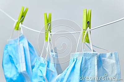 Disposable blue medical surgical mask hanging on peggs clothesline for reused after washing. Coronavirus, SARS-CoV-2 prevention. Stock Photo