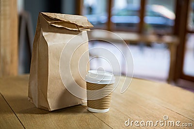 Disposable coffee cup and paper bag on table in cafe Stock Photo