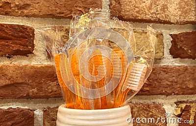 Disposable orange toothbrushes against a red brick wall. Oral care tools Stock Photo