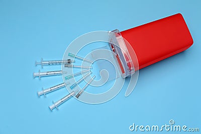 Disposable syringes, needles and sharps container on light blue background Stock Photo