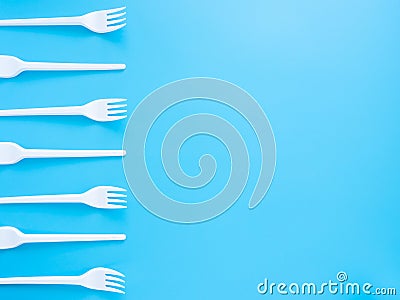 Disposable tableware, white plastic forks isolated on a blue background with copy space. Modern problems of plastic product Stock Photo