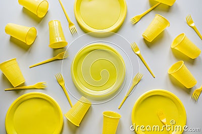 Disposable yellow picnic utensils on grey. Environment eco friendly discarded plastic garbage collection for recycle concept.Top Stock Photo