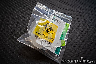 Disposal of Covid 19 saliva test kit in a plastic bag after use. Biohazard specimen bag Editorial Stock Photo